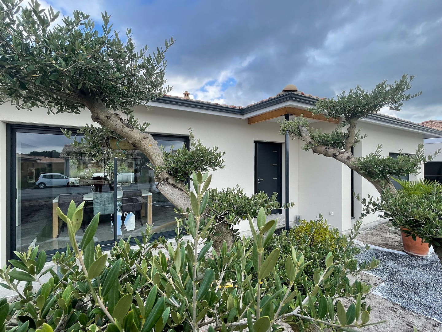 Maison moderne avec jardin, grande baie vitrée, porte d'entrée, garage